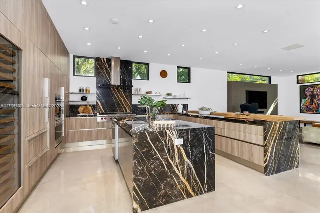 a kitchen with stainless steel appliances kitchen island granite countertop a refrigerator and a sink