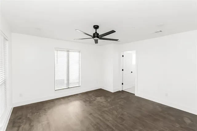 an empty room with chandelier fan and windows