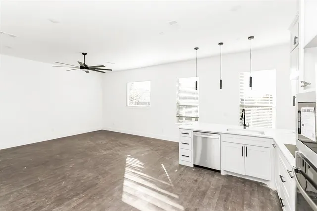 a kitchen with stainless steel appliances a sink a stove a refrigerator and white cabinets