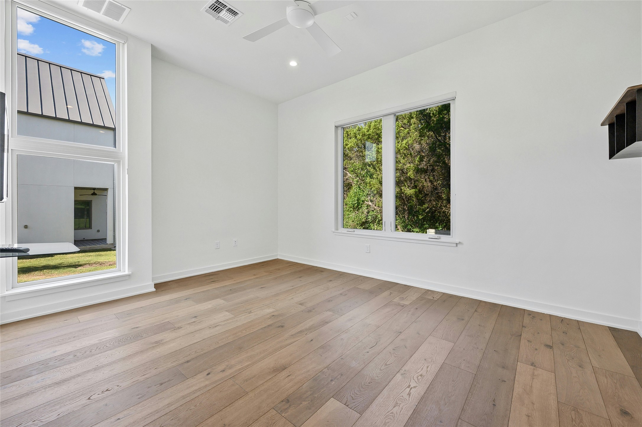 2518 Sutherland Street Austin, TX 78746 - Photo 27 of 30 Hardwood floors and a modern ceiling fan elevate this naturally illuminated living space.