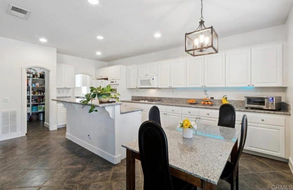 1234 Old Janal Ranch Road Chula Vista, CA 91915 - Photo 15 of 34 a kitchen with a dining table chairs refrigerator and cabinets