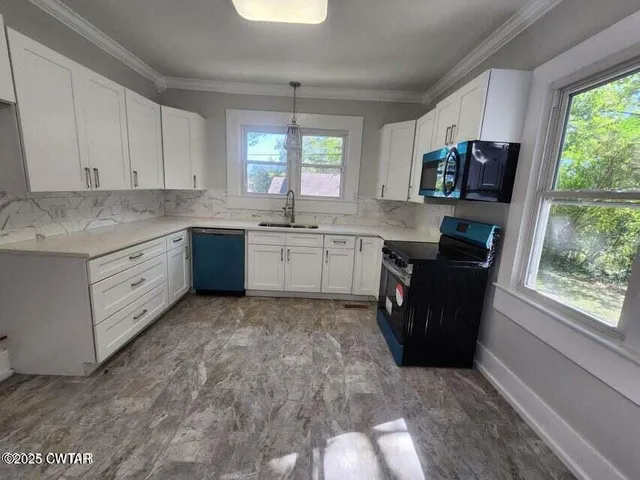a kitchen with granite countertop a stove a sink dishwasher and a microwave oven with white cabinets