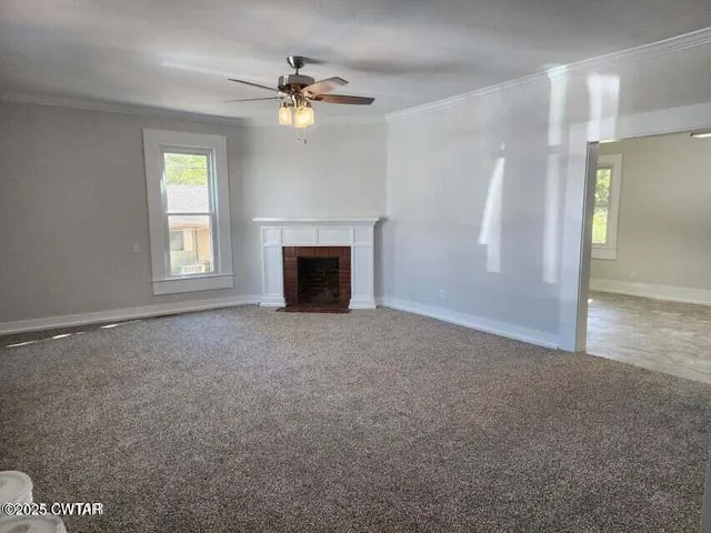 an empty room with windows and fireplace