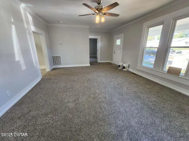an empty room with windows and fan