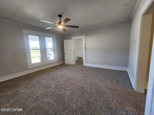 an empty room with windows and fan