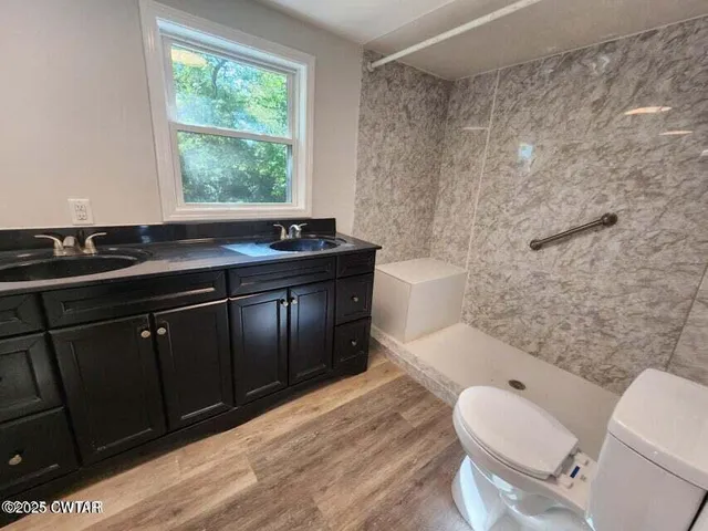 a bathroom with a granite countertop toilet a sink a mirror and a bathtub