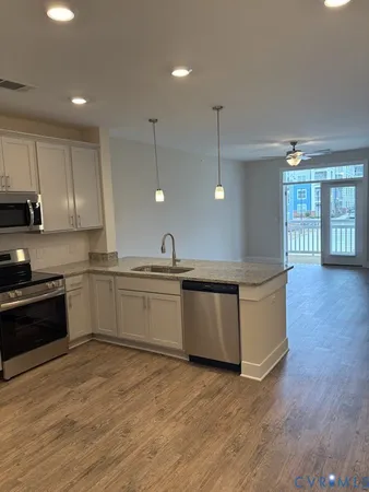 a large kitchen with stainless steel appliances a large counter top a stove a sink a refrigerator and a window