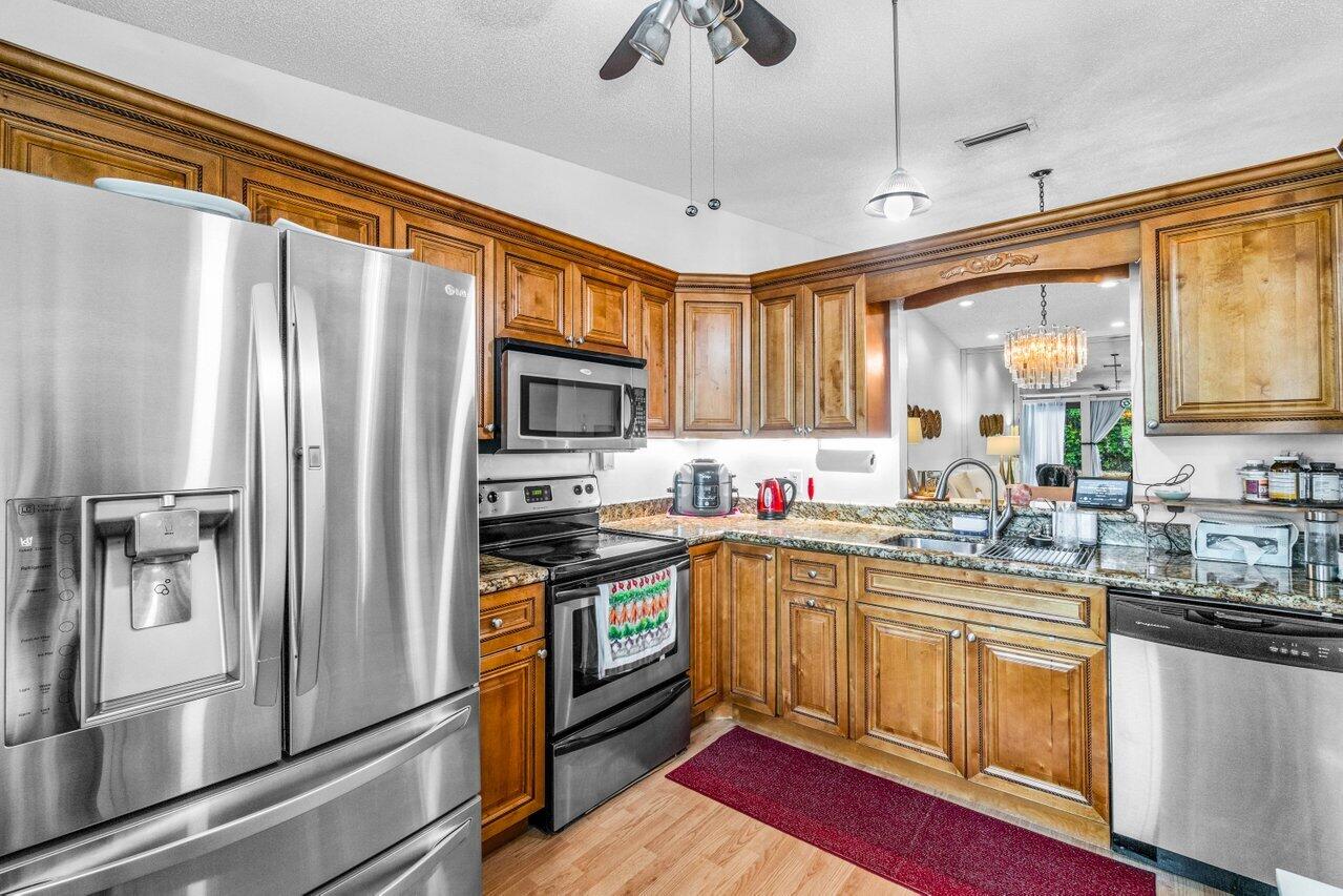 18855 Candlewick Drive Boca Raton, FL 33496 - Photo 8 of 27 a kitchen with stainless steel appliances granite countertop a refrigerator a sink a stove and white cabinets with wooden floor