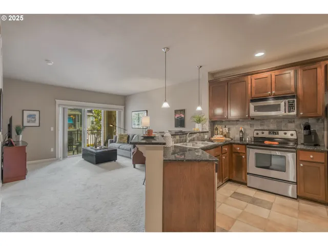 a kitchen with stainless steel appliances granite countertop a stove top oven a sink dishwasher a dining table and chairs with wooden floor