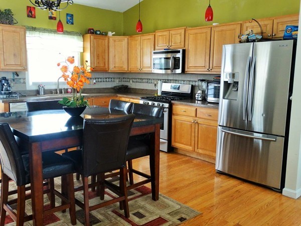 24 Curtis Street Springfield, MA 01119 - Photo 3 of 17 a kitchen with stainless steel appliances granite countertop a refrigerator a stove a sink a dining table and chairs with wooden floor