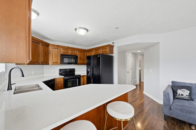 116 East Resaca Drive, Unit F6 Sandy, UT 84070 - Photo 13 of 32 Kitchen featuring wood cabinetry, white countertops, a stainless steel double basin sink with a black faucet, and hardwood-style flooring