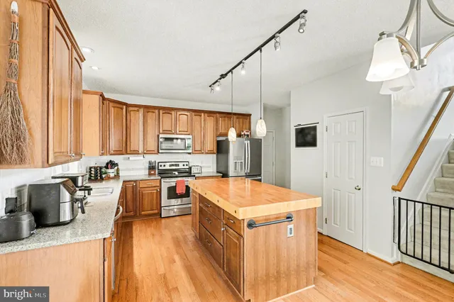 a kitchen with stainless steel appliances granite countertop a stove a sink dishwasher and a refrigerator with wooden floor