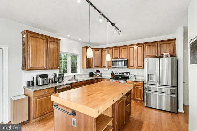 a kitchen with refrigerator a stove a sink and dishwasher with wooden floor