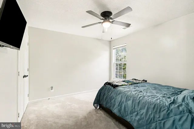 a bedroom with a bed and a flat tv screen on dresser