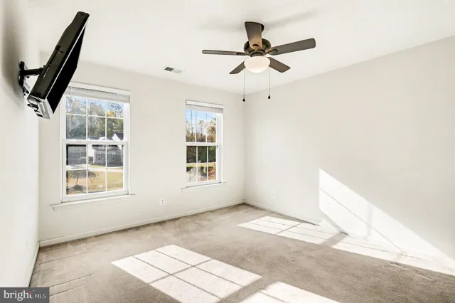 an empty room with windows and fan