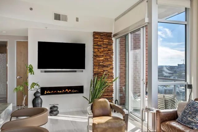 a living room with furniture a flat screen tv and a floor to ceiling window