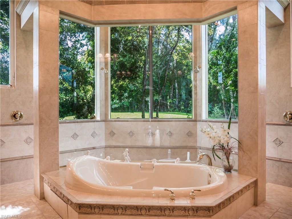 136 Hickory Road Naples, FL 34108 - Photo 18 of 34 Jacuzzi tub in the master offers views to the back yard. Double shower just to the back.