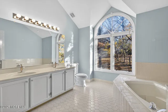 a spacious bathroom with a double vanity sink a large mirror and a bathtub