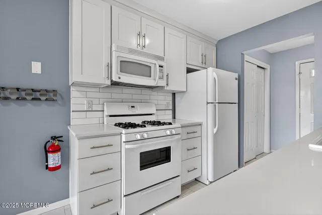 a kitchen with white cabinets and white appliances