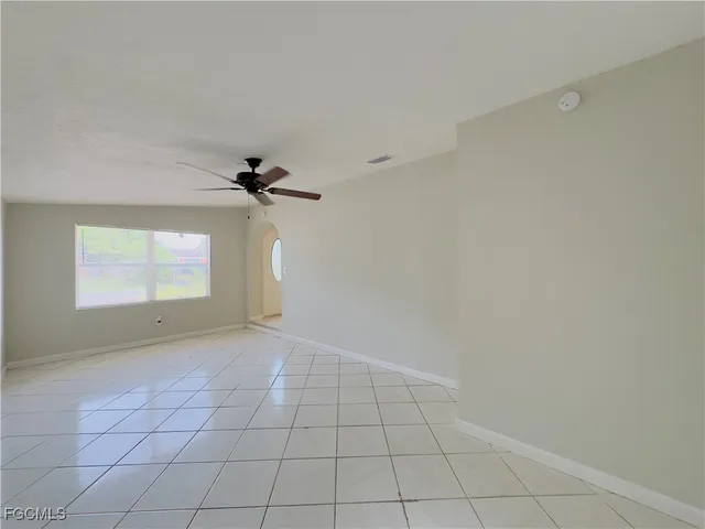 an empty room with windows and ceiling fan