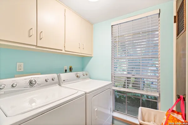 a view of washer and dryer with bathroom in the background