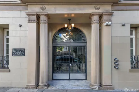 a front view of a building with lot of cars and trees