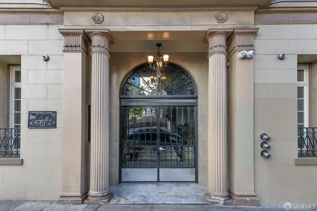 a front view of a building with lot of cars and trees