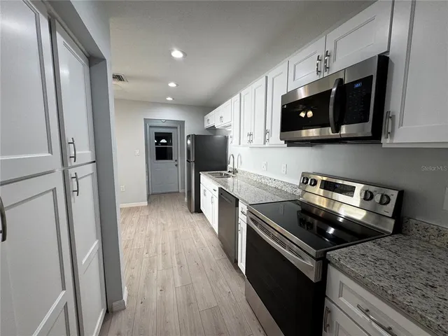 a kitchen with stainless steel appliances granite countertop a stove microwave and sink