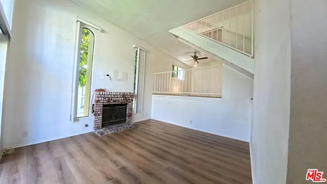 a view of a livingroom with wooden floor fireplace and staircase