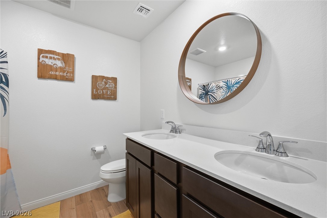 3705 Alla Rocca Avenue Henderson, NV 89044 - Photo 7 of 50 This bathroom (downstairs) features dual sinks and warm wood flooring, offering convenience and a cozy atmosphere.