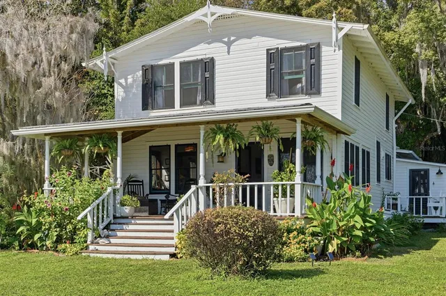 a view of a house with a small yard plants and large trees
