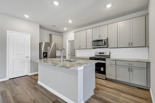 a kitchen with stainless steel appliances granite countertop a stove a sink and a refrigerator