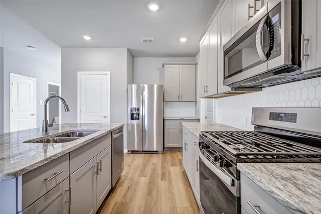 a kitchen with stainless steel appliances granite countertop a sink stove and refrigerator