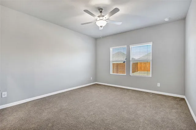 an empty room with windows and ceiling fan