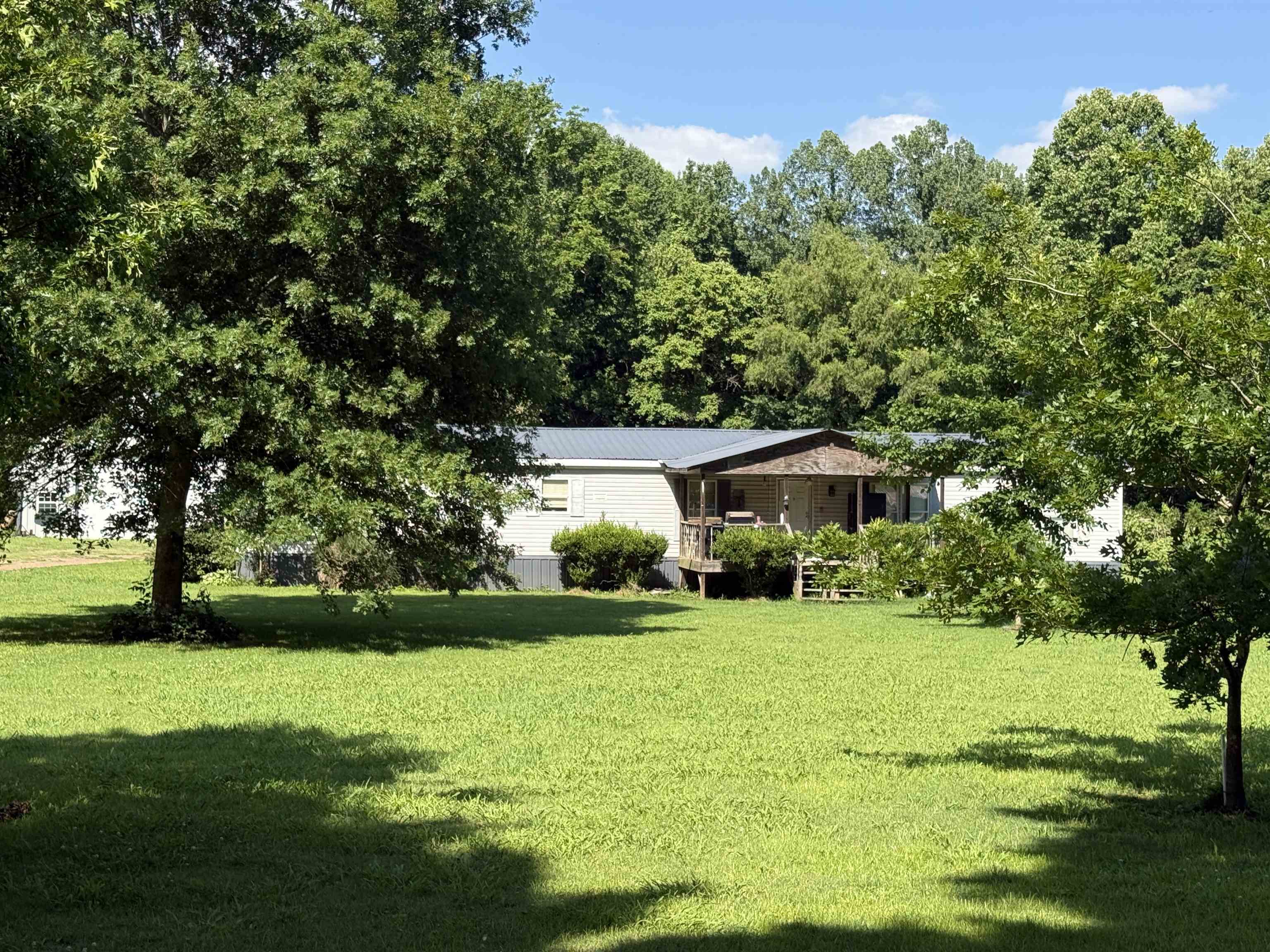 2572 Jeff Webb Road Ripley, TN 38063 - Photo 1 of 1 Expansive green lawn with mature trees and a residence featuring a covered porch and metal roof