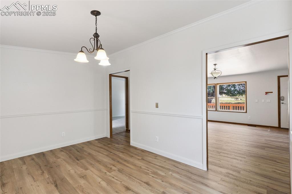 16175 Cathys Loop Peyton, CO 80831 - Photo 18 of 35 an empty room with wooden floor chandelier and windows