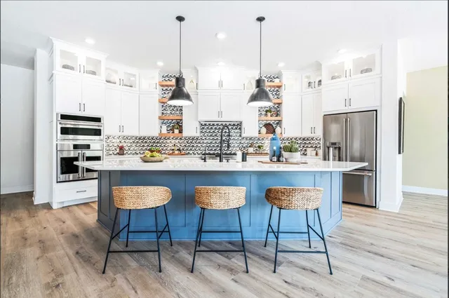 a kitchen with stainless steel appliances kitchen island granite countertop a refrigerator a stove a kitchen island and chairs with wooden floor