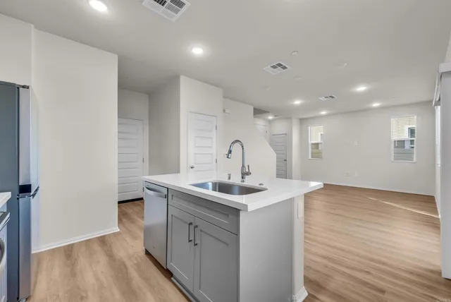 a kitchen with a sink and dishwasher with wooden floor