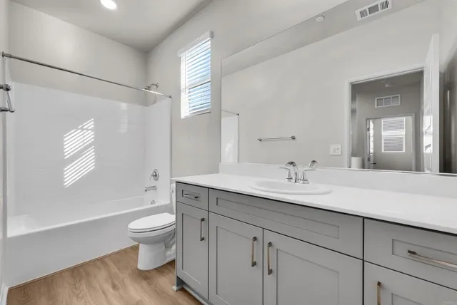 a spacious bathroom with a granite countertop sink toilet a large mirror a bathtub and shower