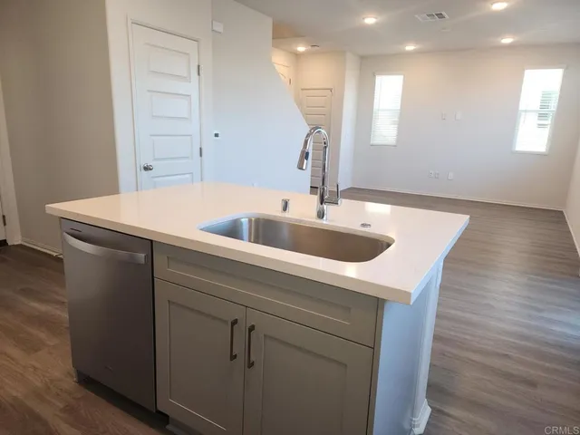 a kitchen with a sink a wooden floor and white cabinet