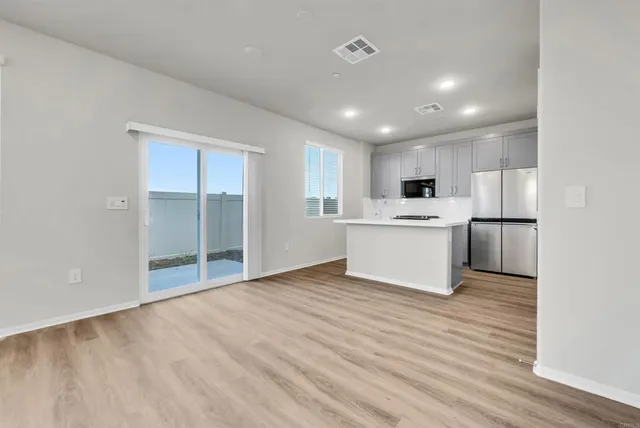 a view of kitchen with refrigerator and white cabinets