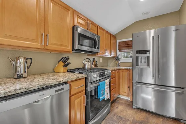 a kitchen with stainless steel appliances granite countertop a refrigerator stove top oven and sink