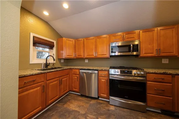 a kitchen with stainless steel appliances granite countertop wooden cabinets stove top oven and sink
