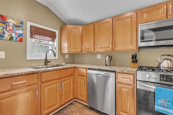 a kitchen with granite countertop cabinets stainless steel appliances a sink and window