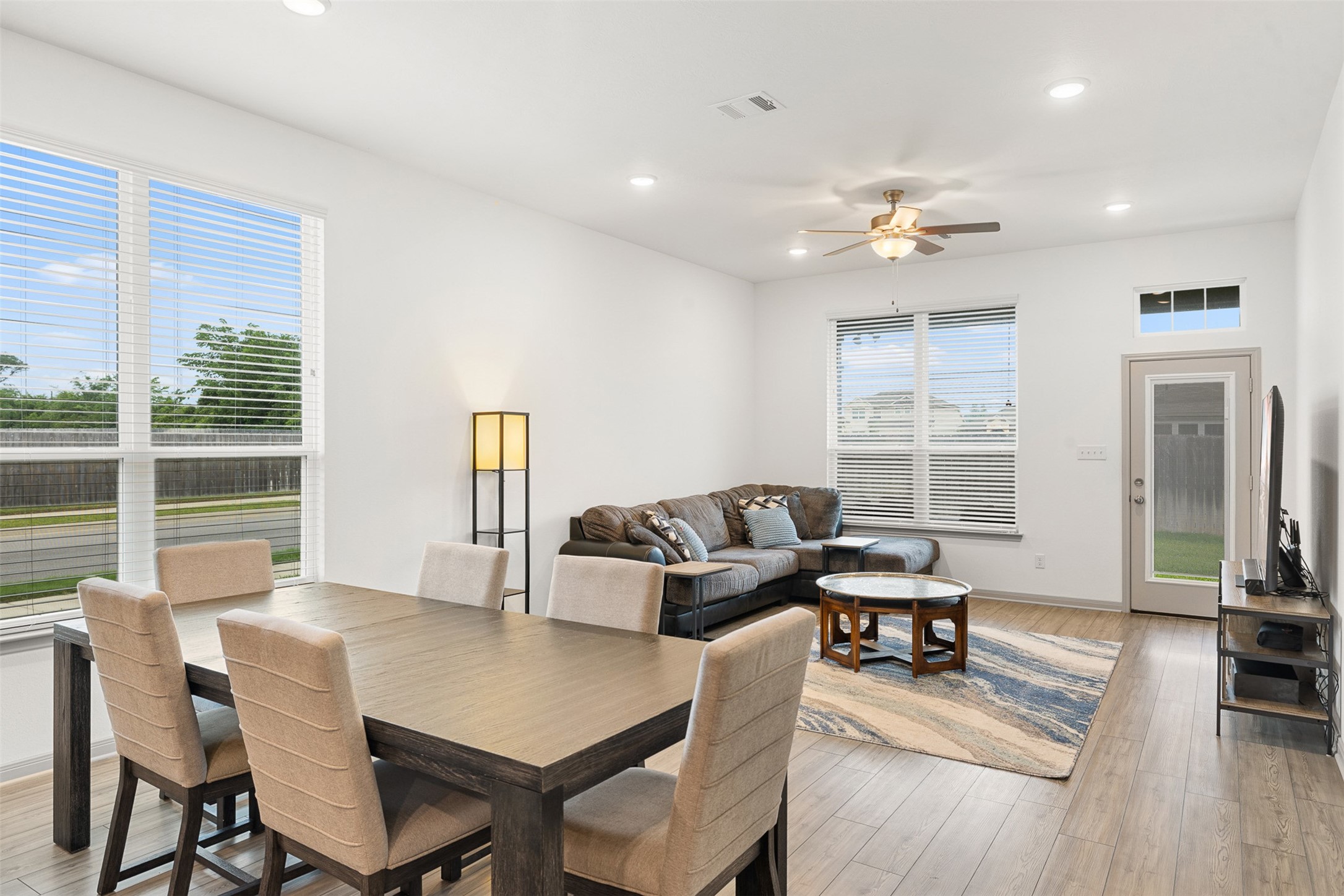 1968 Chief Street Bryan, TX 77807 - Photo 1 of 27 This photo showcases a bright, open-concept living and dining area with large windows, allowing ample natural light. The space features hardwood floors, and a ceiling fan, offering a cozy and inviting atmosphere.