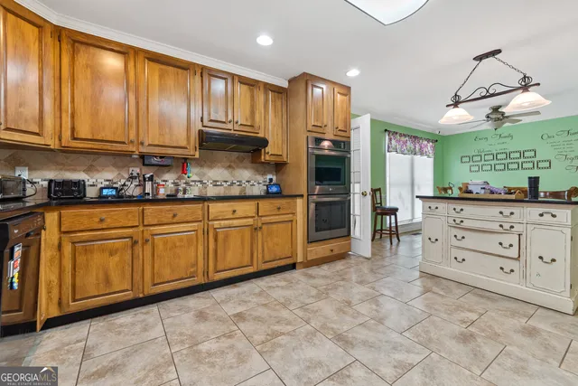 a kitchen with granite countertop a stove a sink a dining table and chairs