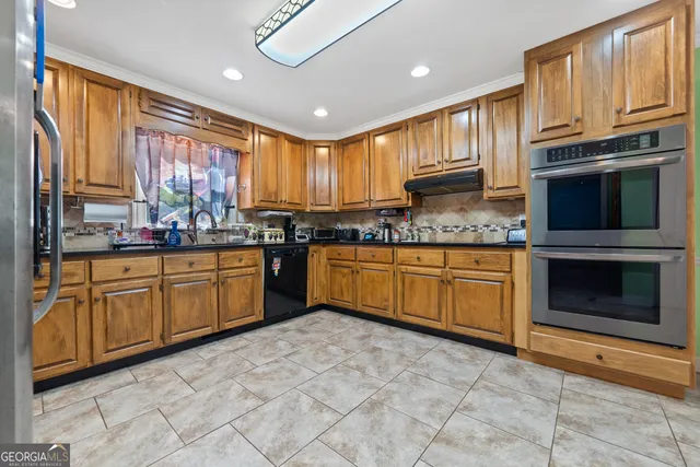 a kitchen with stainless steel appliances granite countertop a sink a stove a refrigerator cabinets and a kitchen island