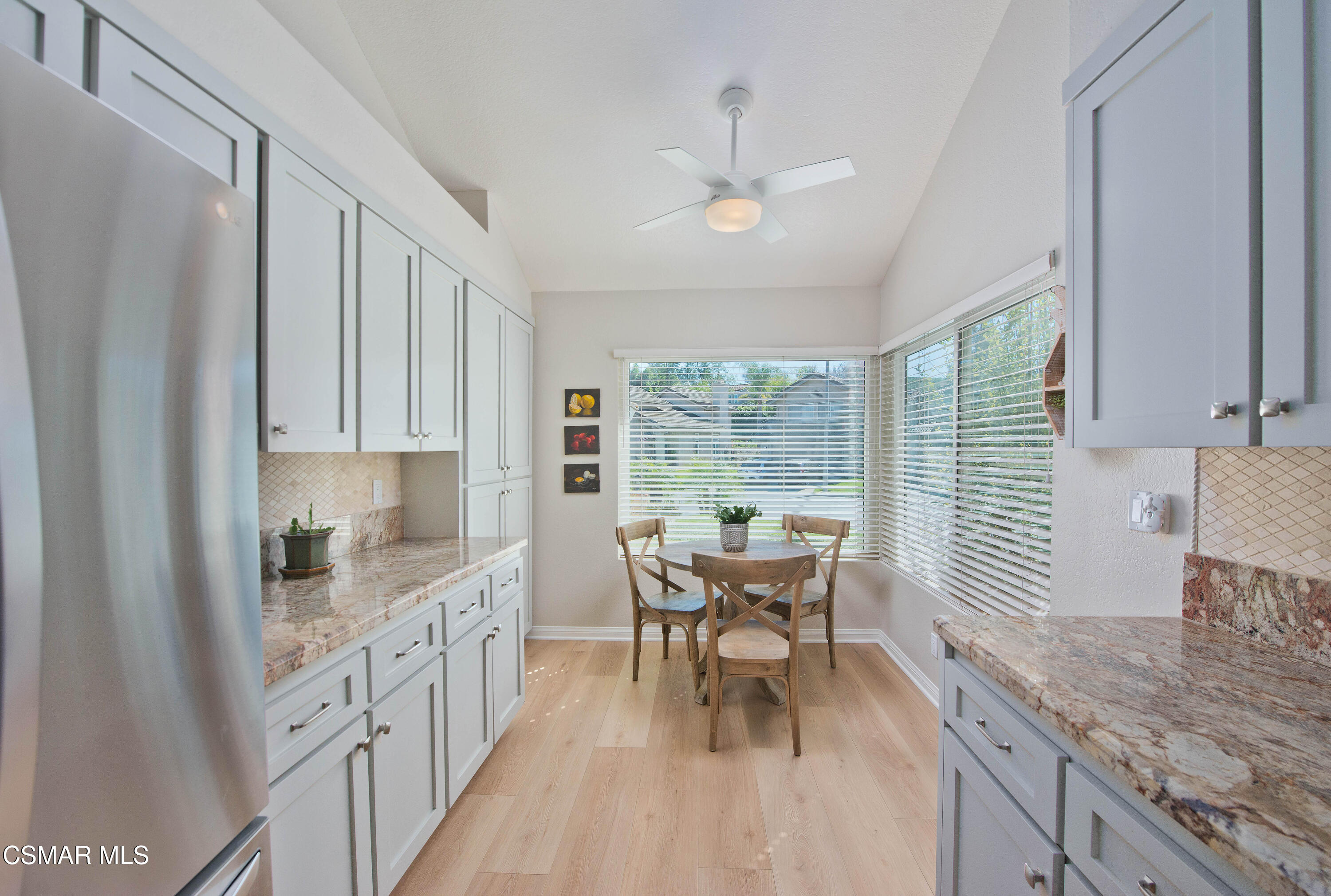 65 Iron Ridge Lane Simi Valley, CA 93065 - Photo 12 of 33 a large white kitchen with granite countertop a sink dishwasher a dining table and chairs with wooden floor