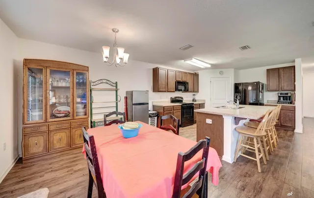 a kitchen with stainless steel appliances a dining table chairs refrigerator and microwave