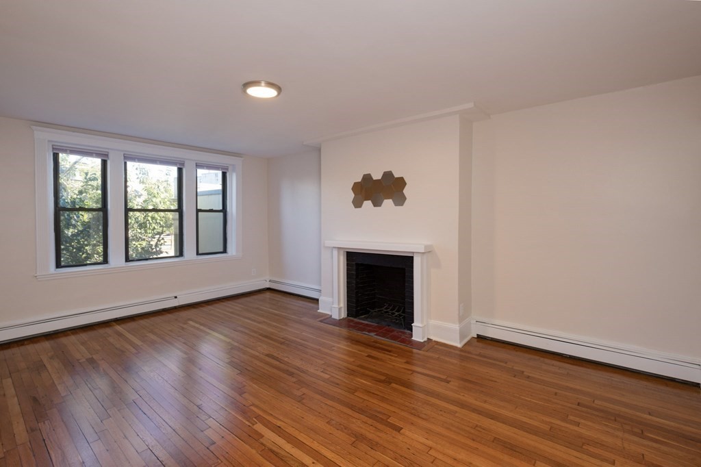 an empty room with wooden floor and a fireplace
